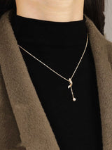 Full Diamond Geometric Tassel Pearl Necklace Clavicle Chain worn by a model in a black turtleneck and olive green jacket.