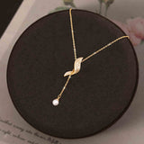 Full Diamond Geometric Tassel Pearl Necklace Clavicle Chain displayed on a dark round jewelry box.